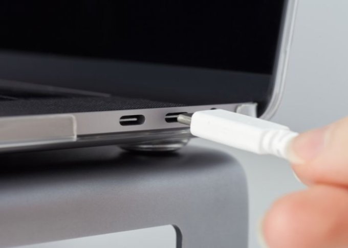 Mężczyzna podpina do laptopa kable USB-C z możliwością przesyłu wideo w jakości 4K